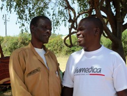 humedica-Mitarbeiter Joshua Ogola (r.) im Gespräch mit Johnston, dem es seit der regelmäßigen Versorgung mit Nahrungsmitteln deutlich besser geht. Foto: humedica/Katja Weber