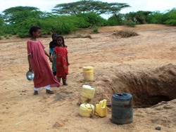 Kinder holen Wasser aus Löchern, die zuvor ins ausgetrocknete Flussbett gegraben wurden. Foto: humedica/Katja Weber.