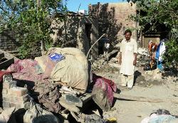 Ein Mann in dem Dorf Bela vor den Überresten seines Hauses. Im Vordergrund die von der Flut völlig durchweichte Bettwäsche und Schulsachen seiner Kinder. Foto: humedica/Daniel Vaupel