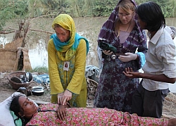 Dr. Petra Kranz-Ries (links, gelbe Burka) und Krankenschwester Saskia Hankel während einer Behandlung direkt am Fluss. Foto: humedica/Simon Gelzenleuchter