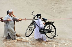 Durch die Wassermassen hindurch versuchen Flutopfer, sich selbst und ihre Habseligkeiten zu retten. Foto: ARO Pakistan
