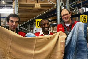 Patrick Khamadi (Mitte) war nach seiner Rückkehr zutiefst bewegt von den Verhältnissen in Syrien und freut sich umso mehr über die Decken. Mit ihm auf dem Bild: Sachbearbeiter Klaus Haas (links) und Logistikchef Hermann Schäffler. Foto: humedica/Steffen Richter