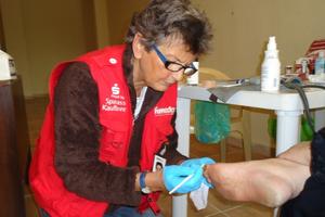 Versorgungen auf dem Boden, als Behandlungszimmer dient eine Konstruktion aus Plastiktisch und festgeklebtem Müllbeutel: auch wenn die vertrauten Gewohnheiten sich ändern, gibt es Alltag. Foto: humedica/Heidi Nicklin