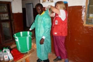 Dr. Sabine Kirchner hilft einem medizinischen Mitarbeiter in den Schutzanzug. Korrektes Anlegen der Schutzkleidung ist überlebenswichtig! Foto: humedica
